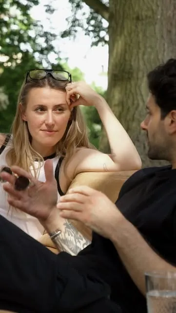 Two people mid-conversation on the sofa outdoors.
